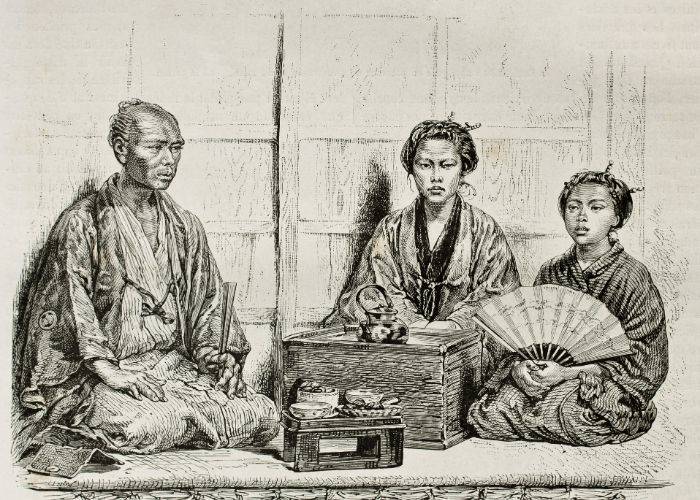 A black-and-white image of a traditional Japanese home, with a man, woman and child sitting around a Japanese tea set.